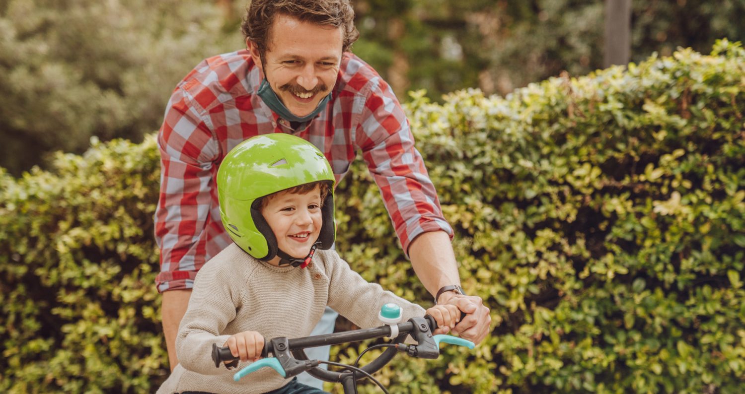 dad teaching child to ride a bike