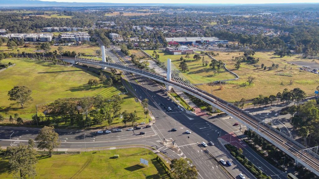 Aerial drone view of a train heading toward Tallawong Station on the metro northwest railway line, Greater Sydney, NSW Australia crossing the railway bridge in June 2024