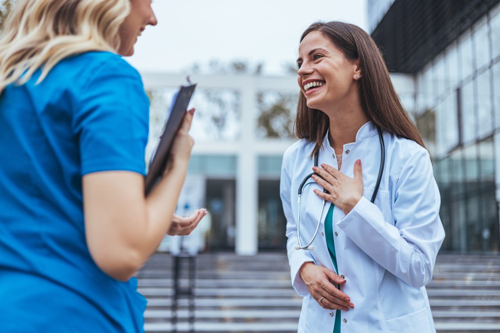 Shot of two medical practitioners using a clipboard together in a hospital. Experienced doctor sharing point of view with colleague. Female nurse and  female doctor discuss patient care