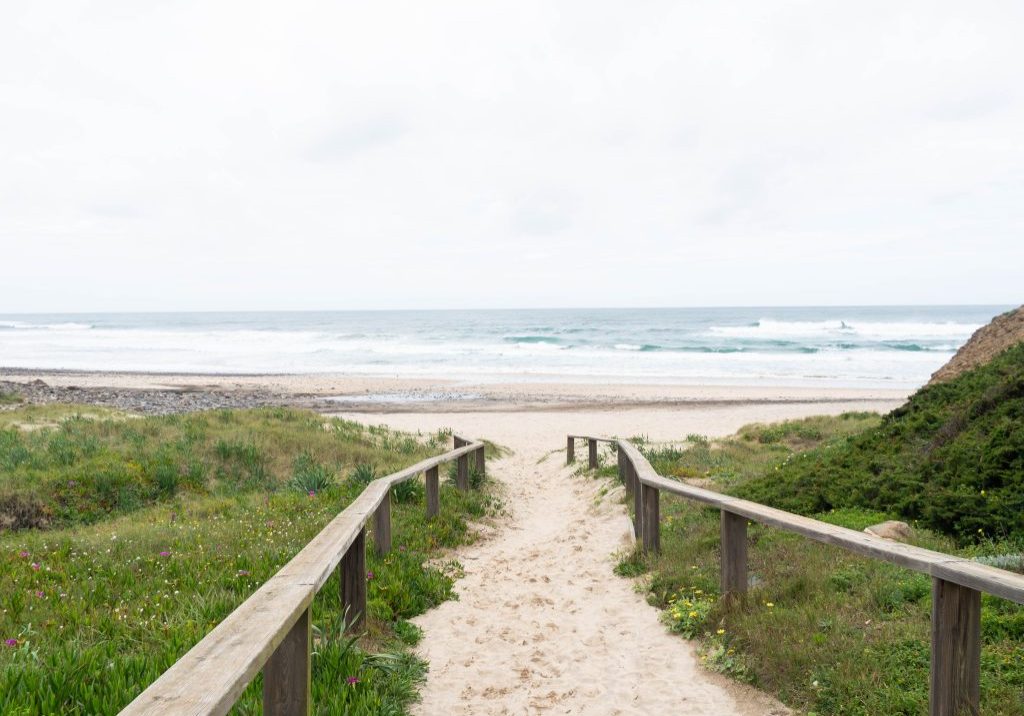 Wooden walkway over the sand of the beach dunes aimed at the empty ocean beach