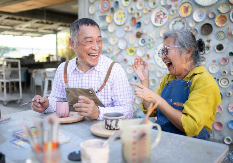 In the pottery workshop, an Asian retired couple is engaged in pottery making and clay painting activities.