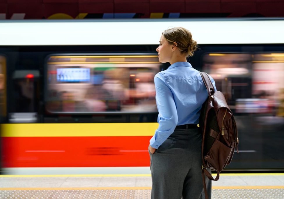 Woman with backpack standing at metro platform with moving train