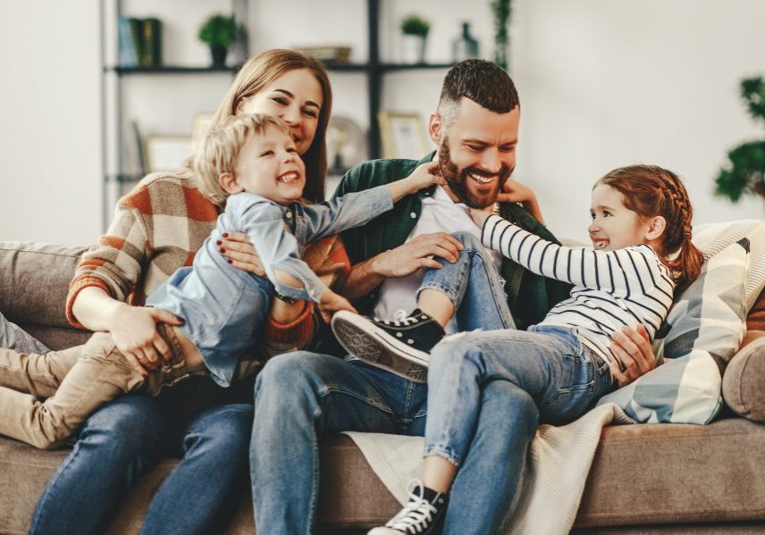 happy family mother father and kids at home on couch