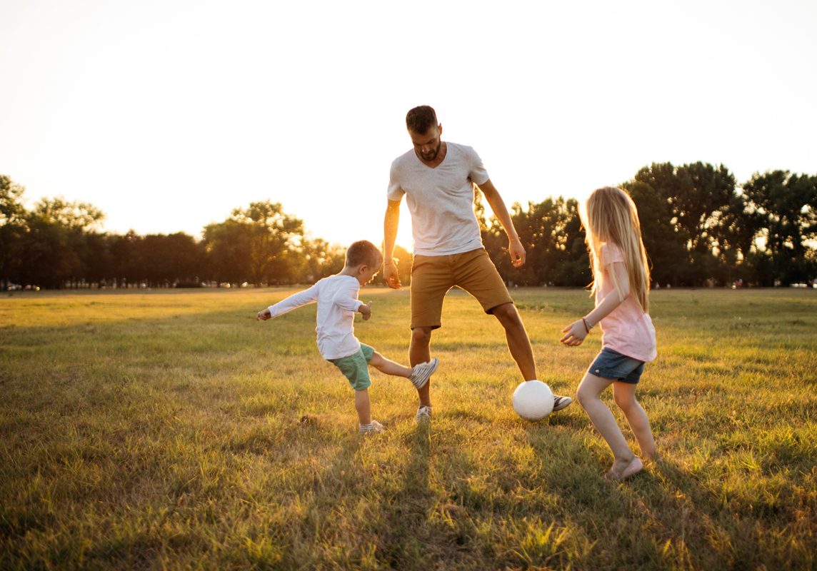 family playing soccer in the park