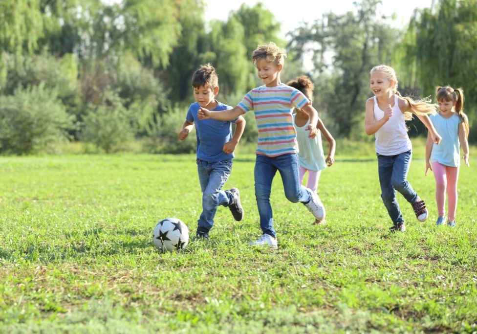 Cute little children playing football outdoors Cute little children playing football outdoors